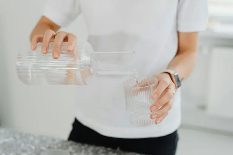 Person häller upp vatten i ett glas