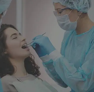 Person blir undersökt av tandhygienist med hjälp av ett redskap