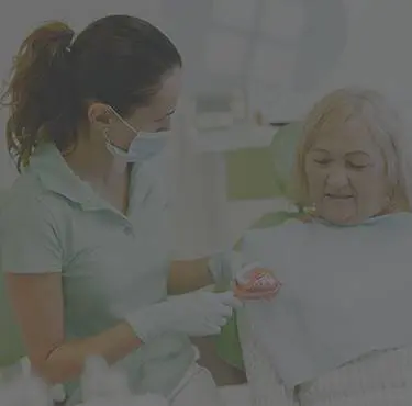 Tandläkare visar upp tandproteser för patient