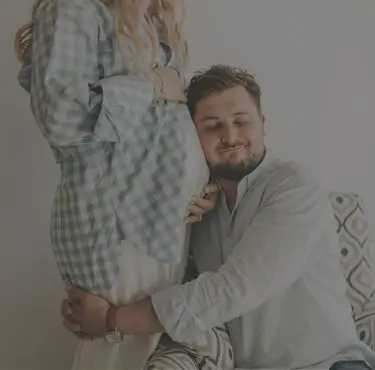 En man lutar sig mot en gravid kvinnas mage.