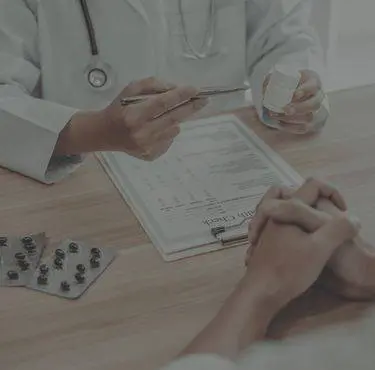 En läkare och en patient sitter mittemot varandra och fyller i ett formulär inför ett företagshälsopaket.