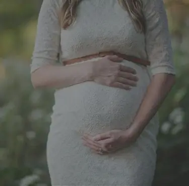 Gravid kvinna som står upp och håller om sin mage