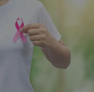 Kvinna med bröstcancer håller i en rosa bandet-band.