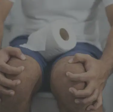 Närbild av man som sitter på toaletten med diarré