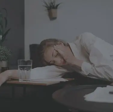 En kvinna ligger lutad över bordet med handen för sitt ansikte.