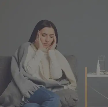 Kvinna med struma sitter ner och håller sina händer på huvudet.