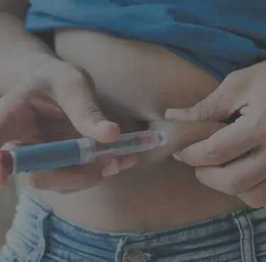 En diabetiker tar en insulinspruta i magen.