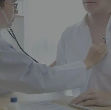 En kardiolog avlyssnar en patients blåsljud på hjärtat.
