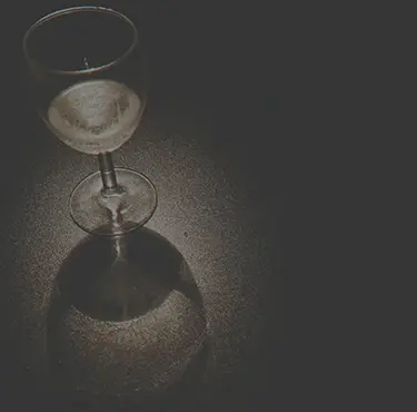 Ett glas vitt vin hos en med alkoholmissbruk står på ett bord.