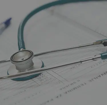 Patient gör ett besök för läkarintyg hos en läkare som lagt stetoskop ovanpå en läkarjournal.