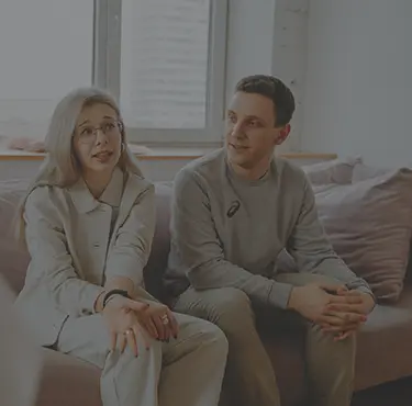 En kvinna och en man sitter i en soffa och pratar med en samtalsterapeut som syns i förgrunden.