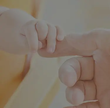 En bebishand som håller i en vuxens hand.
