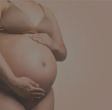 En gravid kvinna i underkläder som håller runt sin mage.