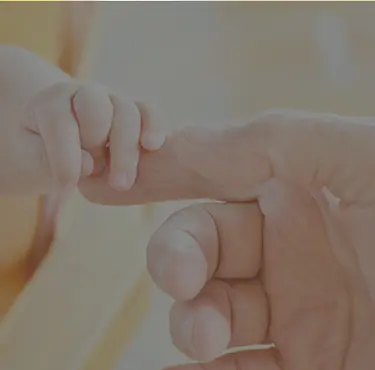 Vuxen hand som håller i en bebis hand.