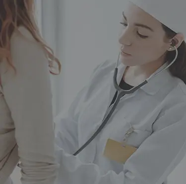 En patient går på läkarbesök hos en allmänläkare som lyssnar på patientens hjärta med stetoskop.