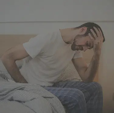 Man med njurinflammation som håller en hand på huvudet av smärta