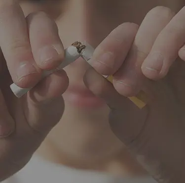 En person som bryter av en cigarett på mitten.