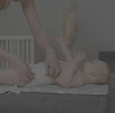 Vuxen person byter blöja på bebis.