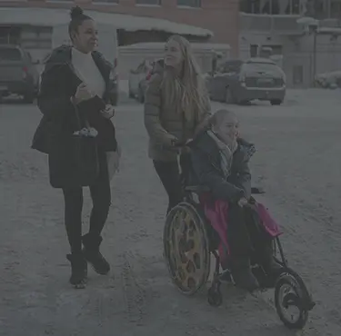 Skrattande flicka blir skjutsad i rullstol