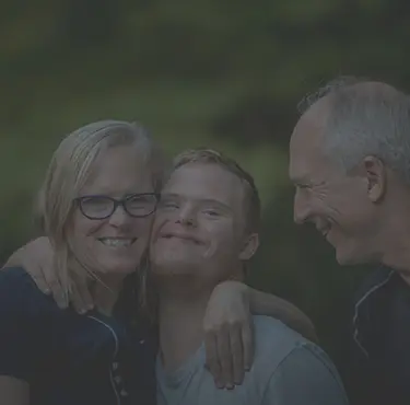 Man med downs syndrom kramar sina föräldrar