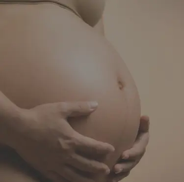 Bild på en gravid kvinna som håller i sin mage.
