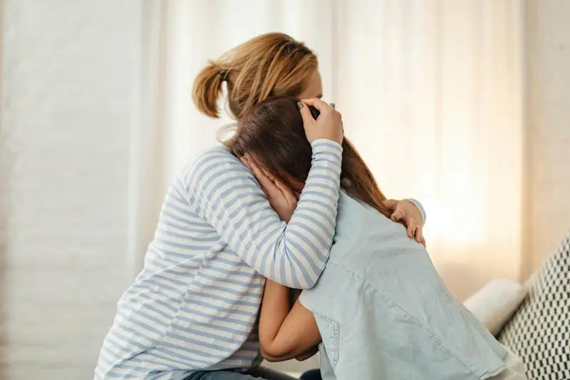 Mamma kramar dotter som är ledsen