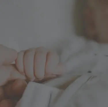 Bild på vuxen hand som håller en bebis hand