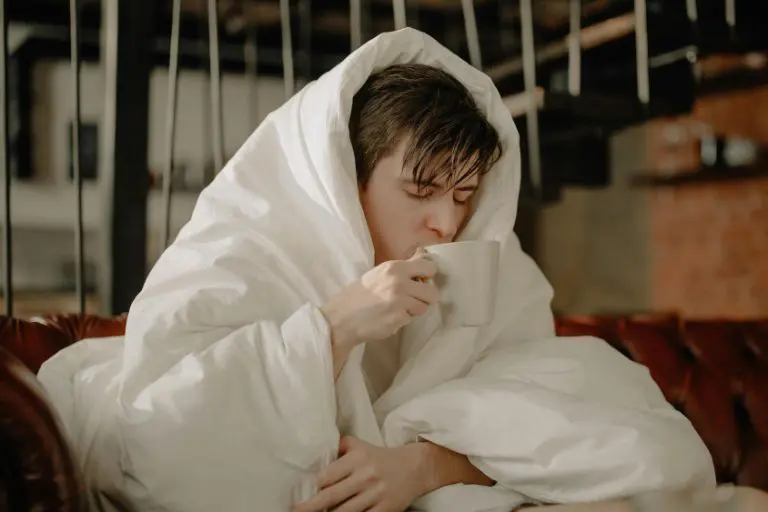 Man covered with blanket drinking tea